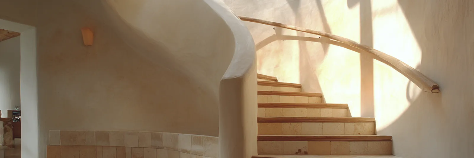 A man sitting on the lower steps of a sunlit stone stairway
